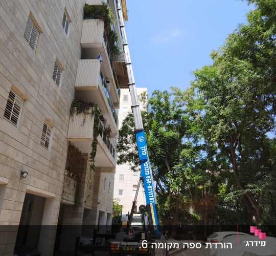 מנוף ליד בניין מגורים עם עצים מסביב